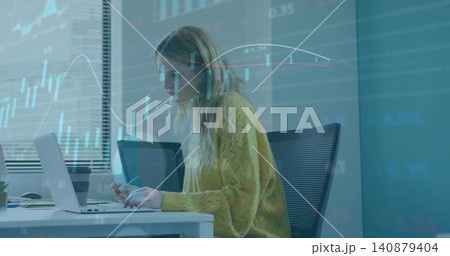 Analyzing woman in yellow sweater checking laptop at office, holding smartphone with stock charts Analyzing woman in yellow sweater checking laptop at office, holding smartphone with stock charts 140879404