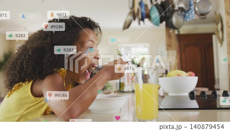 Eating child in yellow tank top leaning on kitchen counter holding bowl and spoon, social overlays 140879454
