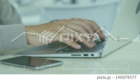 Typing male's hands wearing light gray cuff on laptop at home desk, with smartphone, chart overlay Typing male's hands wearing light gray cuff on laptop at home desk, with smartphone, chart overlay 140879577