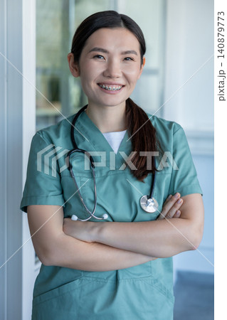 Cute young female doctor in lab coat and with stethoscope around her neck Cute young female doctor in lab coat and with stethoscope around her neck 140879773