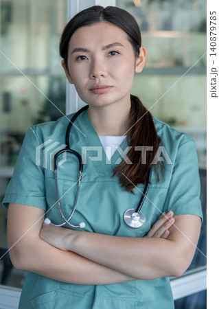 Cute young female doctor in lab coat and with stethoscope around her neck Cute young female doctor in lab coat and with stethoscope around her neck 140879785
