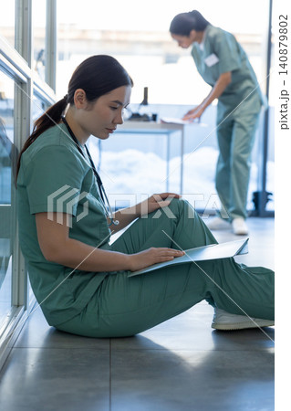 Doctor in a lab coat sitting on the floor and reading medical history of the patient Doctor in a lab coat sitting on the floor and reading medical history of the patient 140879802