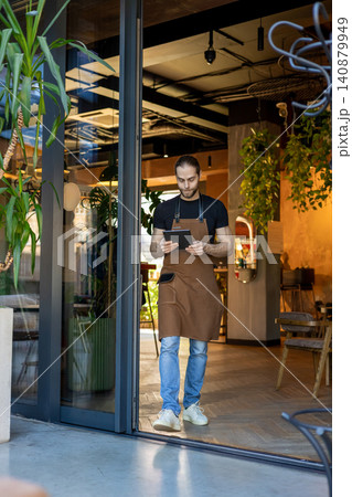 Manager entering cafe with digital tablet 140879949