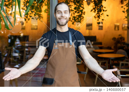 Friendly man in apron gesturing welcome with open arms 140880037