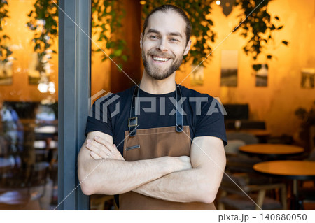 Happy bearded man wearing apron standing with crossed arms 140880050