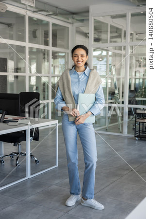 Young businesswoman standing with folder in office Young businesswoman standing with folder in office 140880504