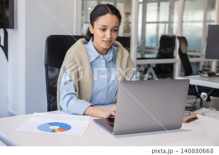Businesswoman working on laptop with charts in office 140880668