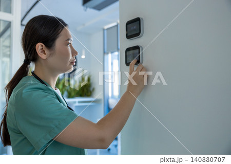 Dark-haired female doctor in lab coat setting the temperature range in a room 140880707