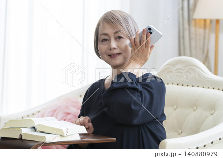 ソファーに座りスマホで英会話の学習をするシニア女性 ソファーに座りスマホで英会話の学習をするシニア女性 140880979