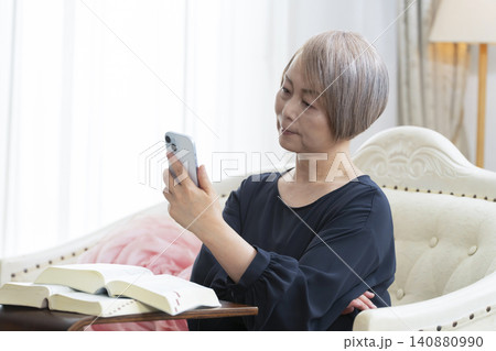 ソファーに座りスマホで英会話の学習をするシニア女性 ソファーに座りスマホで英会話の学習をするシニア女性 140880990
