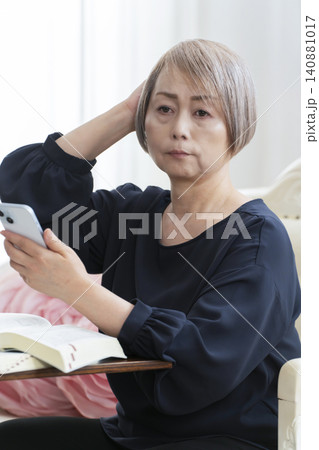 ソファーに座りスマホで英会話の学習をするシニア女性 ソファーに座りスマホで英会話の学習をするシニア女性 140881017