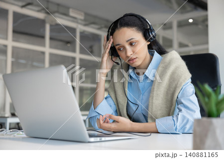Tired woman in headset working on laptop Tired woman in headset working on laptop 140881165