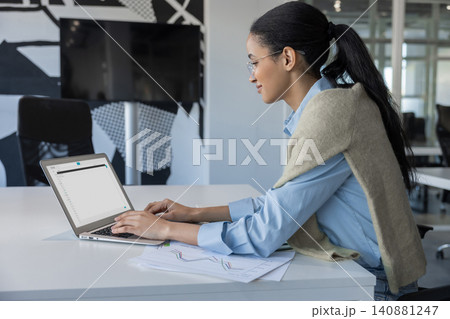Profile of woman typing on laptop with charts Profile of woman typing on laptop with charts 140881247