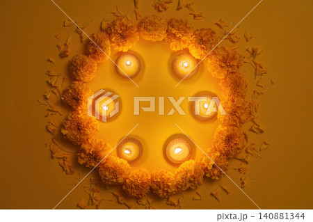 Diwali festival concept with burning clay diyas and marigold flower wreath on yellow background 140881344