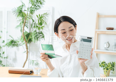 笑顔で通帳と電卓を持つ女性。貯金、マネー、投資、資産運用、財テク、ショッピング、ローン、お得、セール 笑顔で通帳と電卓を持つ女性。貯金、マネー、投資、資産運用、財テク、ショッピング、ローン、お得、セール 140881379