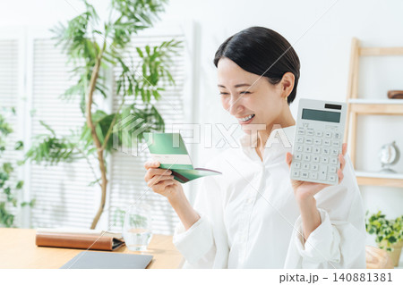 笑顔で通帳と電卓を持つ女性。貯金、マネー、投資、資産運用、財テク、ショッピング、ローン、お得、セール 笑顔で通帳と電卓を持つ女性。貯金、マネー、投資、資産運用、財テク、ショッピング、ローン、お得、セール 140881381