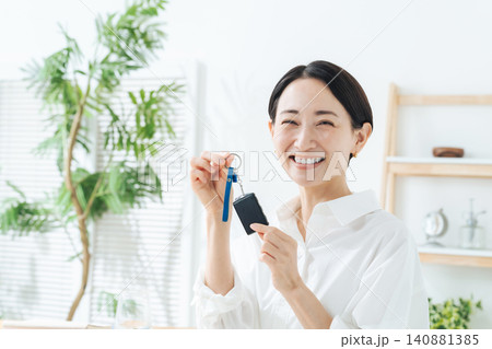 自動車のスマートキーを持つ女性。マイカー、納車、レンタカー、カーシェア、ドライバー、運転、ディーラー 140881385