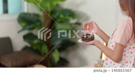 Close up of girl holding small chocolate birthday cake with lit candle Close up of girl holding small chocolate birthday cake with lit candle 140881567