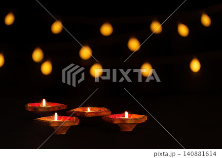 Lit clay diyas on dark background with warm bokeh lights for Diwali festival Lit clay diyas on dark background with warm bokeh lights for Diwali festival 140881614