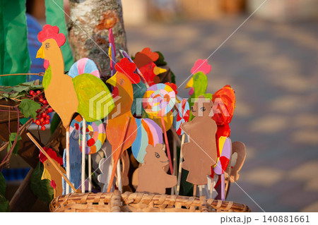 Colorful handmade chicken decorations displayed at a crafts market in a sunny outdoor setting 140881661