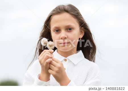 Young girl holding flower buds in a serene outdoor setting on a cloudy day Young girl holding flower buds in a serene outdoor setting on a cloudy day 140881822