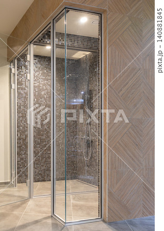 glass shower room, dark mosaic tile interior and a geometric wooden wall pattern in a luxury spa glass shower room, dark mosaic tile interior and a geometric wooden wall pattern in a luxury spa 140881845
