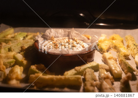 camembert cheese with herbs and breaded zucchini fries baking inside dark oven camembert cheese with herbs and breaded zucchini fries baking inside dark oven 140881867