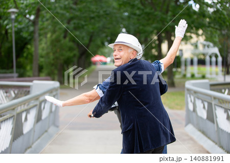 Elderly man enjoying a playful moment in a park while dressed in stylish attire during a sunny afternoon Elderly man enjoying a playful moment in a park while dressed in stylish attire during a sunny afternoon 140881991