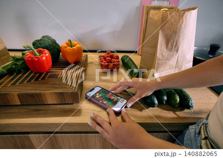 Fresh vegetables and smartphone grocery app on kitchen counter. 140882065