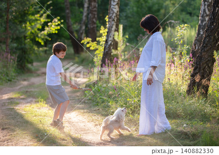 The family enjoys a playful day in a sunny forest with a dog and a child engaged in carefree fun. The family enjoys a playful day in a sunny forest with a dog and a child engaged in carefree fun. 140882330