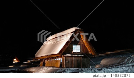 夜の雪の積もった茅葺き家屋 140882875