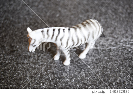 The toy zebra. Plastic toy on the floor. 140882983