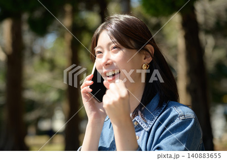公園で電話しながらガッツポーズをする日本人女性 140883655