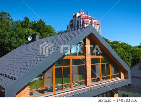 House with a gray metal roof and large windows on the facade. Corrugated metal roof and metal roofing. Modern roof made of metal. House with a gray metal roof and large windows on the facade. Corrugated metal roof and metal roofing. Modern roof made of metal. 140883816