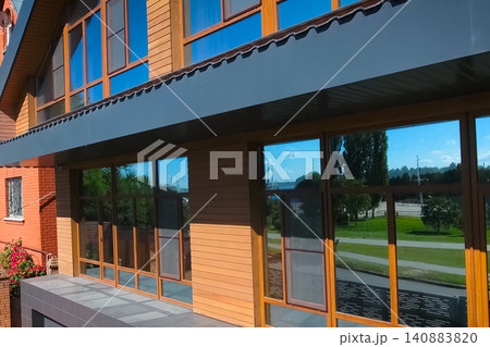 House with a gray metal roof and large windows on the facade. Corrugated metal roof and metal roofing. Modern roof made of metal. House with a gray metal roof and large windows on the facade. Corrugated metal roof and metal roofing. Modern roof made of metal. 140883820