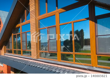 House with a gray metal roof and large windows on the facade. Corrugated metal roof and metal roofing. Modern roof made of metal. House with a gray metal roof and large windows on the facade. Corrugated metal roof and metal roofing. Modern roof made of metal. 140883821