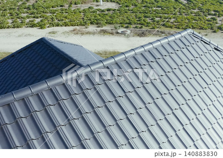 House with a gray metal roof. Corrugated metal roof and metal roofing. Modern roof made of metal. House with a gray metal roof. Corrugated metal roof and metal roofing. Modern roof made of metal. 140883830