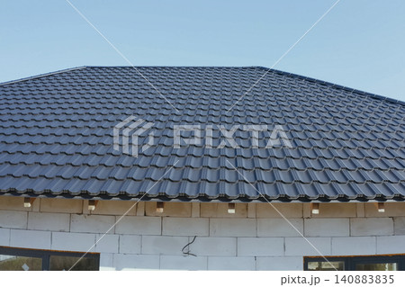 House with a gray metal roof. Corrugated metal roof and metal roofing. Modern roof made of metal. House with a gray metal roof. Corrugated metal roof and metal roofing. Modern roof made of metal. 140883835