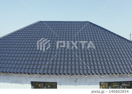 House with a gray metal roof. Corrugated metal roof and metal roofing. Modern roof made of metal. House with a gray metal roof. Corrugated metal roof and metal roofing. Modern roof made of metal. 140883854