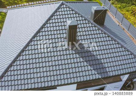House with a gray metal roof. Corrugated metal roof and metal roofing. Modern roof made of metal. 140883889