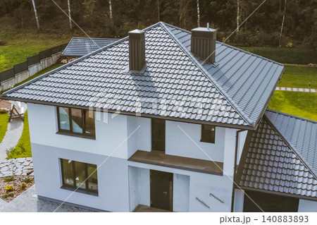 House with a gray metal roof. Corrugated metal roof and metal roofing. Modern roof made of metal. House with a gray metal roof. Corrugated metal roof and metal roofing. Modern roof made of metal. 140883893