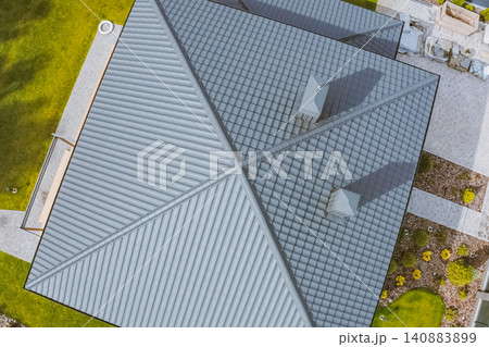 House with a gray metal roof. Corrugated metal roof and metal roofing. Modern roof made of metal. 140883899