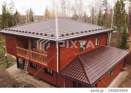 House with a brown metal roof.Corrugated metal roof and metal roofing. Modern roof made of metal. House with a brown metal roof.Corrugated metal roof and metal roofing. Modern roof made of metal. 140883904