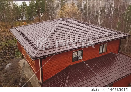 House with a brown metal roof.Corrugated metal roof and metal roofing. Modern roof made of metal. 140883915