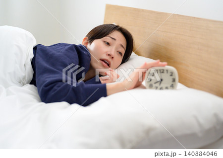 寝不足で目覚まし時計を止める日本人女性 寝不足で目覚まし時計を止める日本人女性 140884046