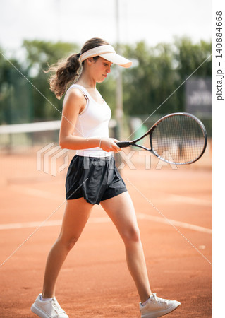 Female tennis player walks on clay court during practice session in the afternoon at local sports club 140884668