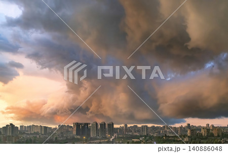 Clouds form over city skyline during sunset with shades of orange, pink, and purple in the sky Clouds form over city skyline during sunset with shades of orange, pink, and purple in the sky 140886048