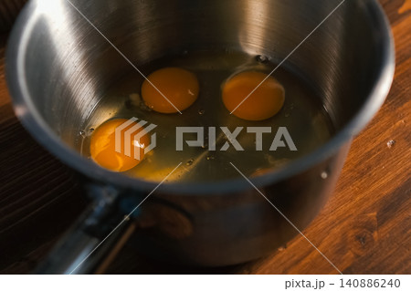 Breaking eggs in pot, raw eggs for beating. Breaking eggs in pot, raw eggs for beating. 140886240