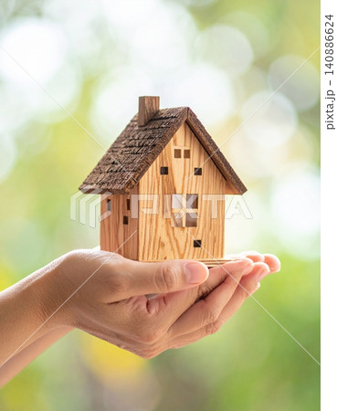 Hands holding a miniature model of a house against a blurred background 140886624