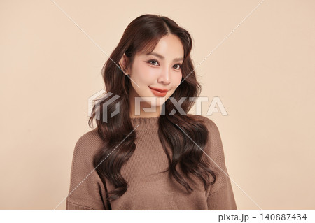 A beautiful young Asian woman with clean, fresh skin against a beige background. Skincare, facial treatment, cosmetology, beauty, and spa. An elegant portrait of an Asian woman. 140887434